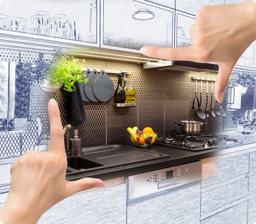 Hands framing a kitchen scene with a combination of a real and sketched kitchen. The real section shows a sink, herbs, utensils, and a gas stove with a pot and fruit bowl.