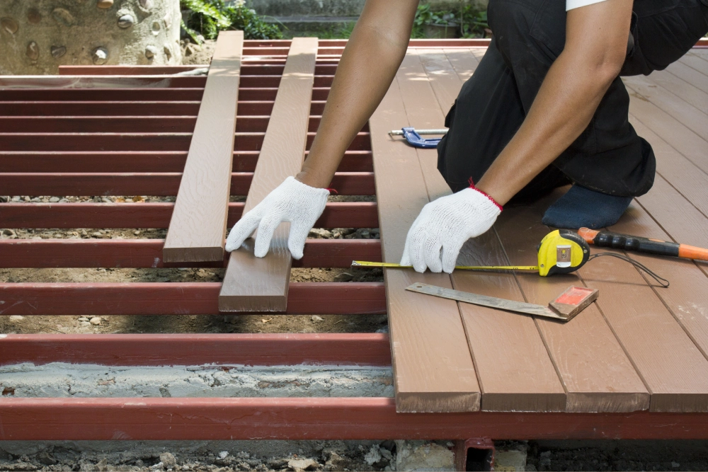 A person measuring and cutting wood on the deck.